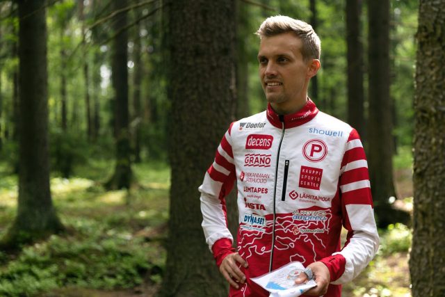 Maajoukkuesuunnistaja Aleksi Niemi seisoo puiden keskellä metsässä
