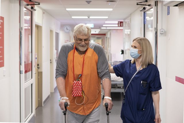 Hoitaja ja potilas kävelevät sydänosaston käytävällä