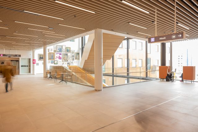 Ahveniston sairaala Assin aula. Aulatila on valoisa, isoista ikkunoista tulee luonnonvaloa. Etualalla näkyy näyttävä portaikko ja sen takana seinällä useita erikokoisia tauluja.