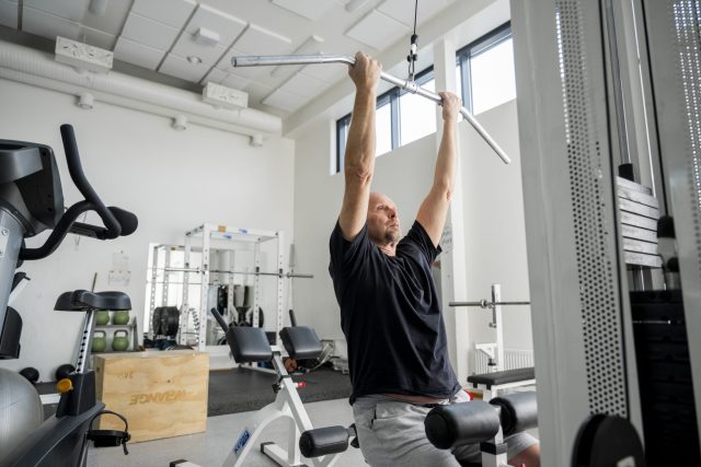 Mies kuntoilee kuntosalilla ja vetää taljaa